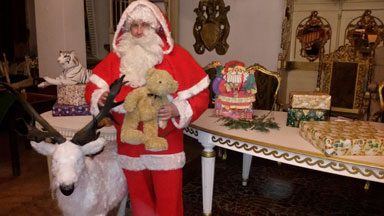Der Weihnachtsmann steht nehmen seinem Rentier und hlt einen Stoffbren in der Hand