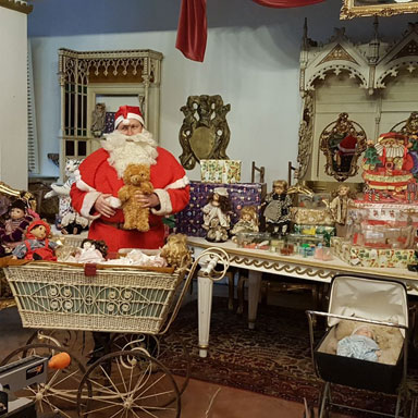 Der Weihnachtsmann steht mit vielen Geschenken in seiner Werkstatt im Knigreich Romkerhall